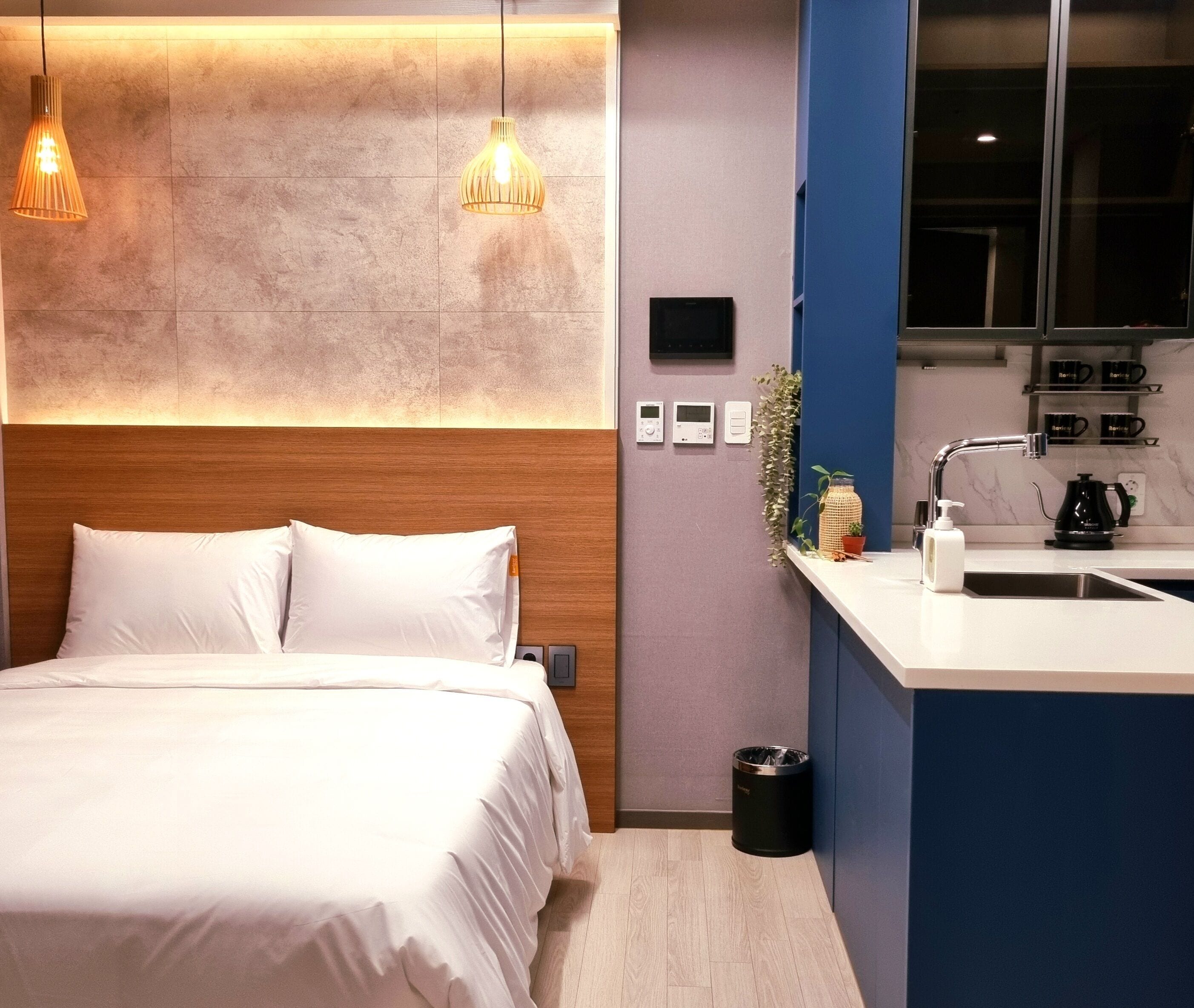 Una habitación de hotel moderna con cama, mesita de noche y una pequeña cocina.