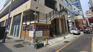 A modern building with multiple floors, large windows, and a prominent staircase leading to the entrance. - Raviens TheBayment Nampo (Busan)