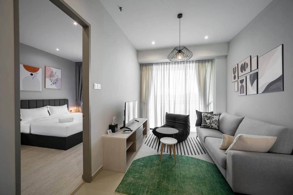 A modern hotel room with a bed, a sofa, a desk, and a chair.