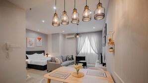 A modern hotel room with a wooden dining table, a sofa, a bed, and a chandelier. - Iconic Regency Service Residences - Managed by Iconic Hotel (George Town)