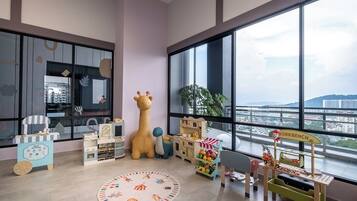 A children's playroom with large windows, a giraffe toy, and various play structures.