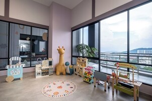 A children's playroom with large windows, a giraffe toy, and various play structures.