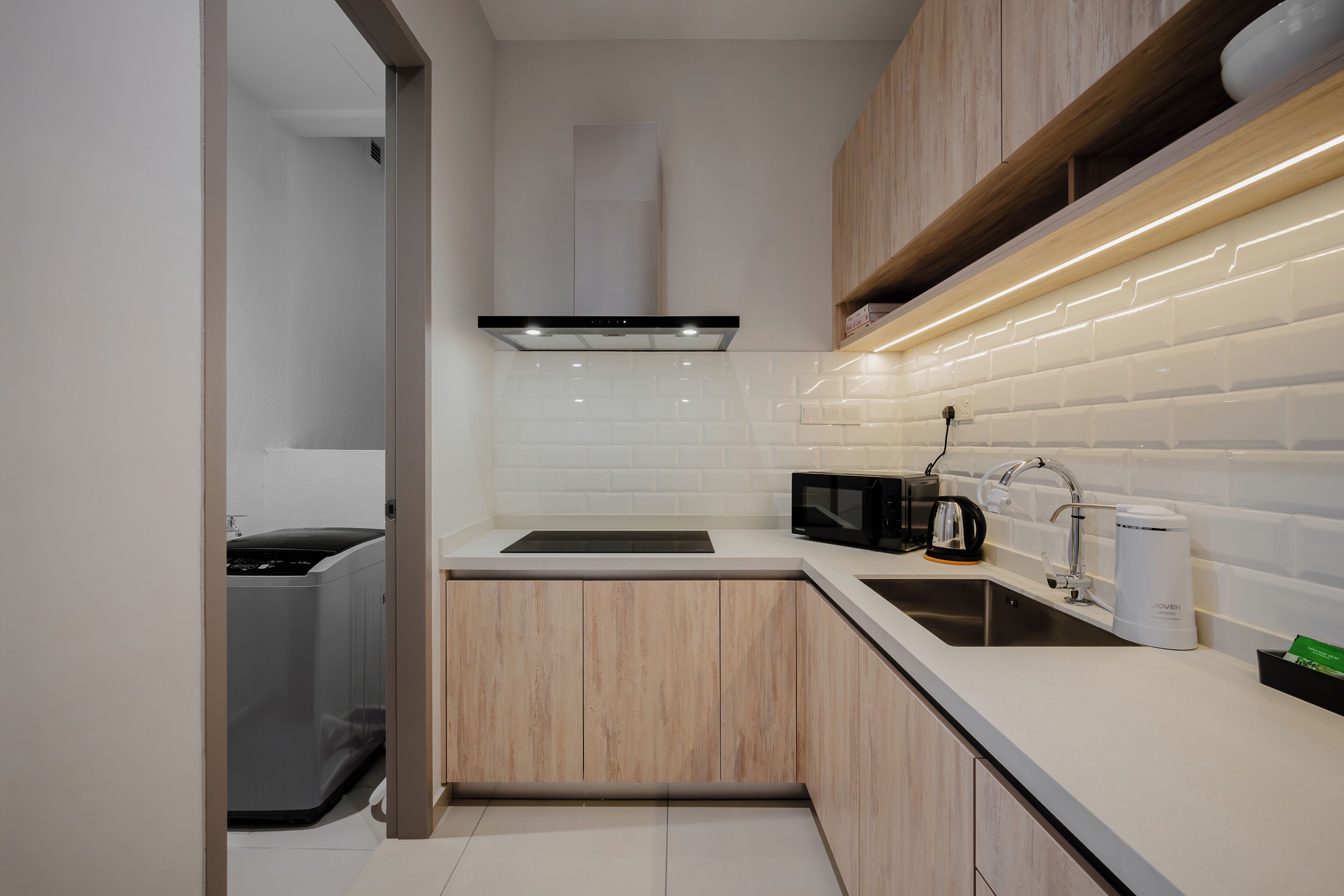 Une cuisine moderne avec des meubles en bois, un évier en acier inoxydable, un four à micro-ondes et un four encastré.