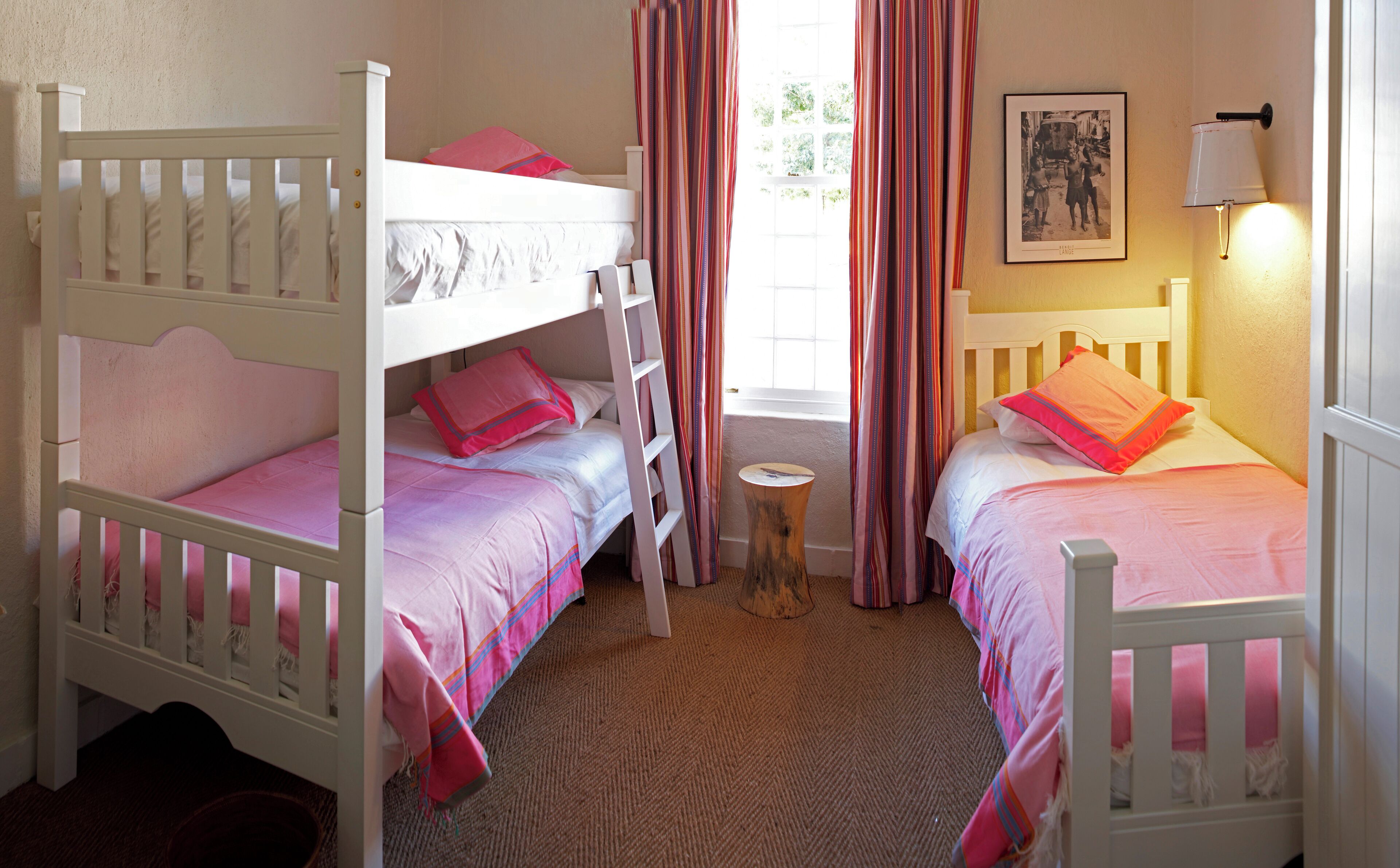 A bedroom with two bunk beds, a small round table, and a window with curtains.