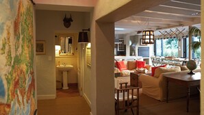 A cozy living room with a sofa, a dining table, and a globe. There is a kitchen area in the background with a sink and a stove. - Explorers Club (Franschhoek)