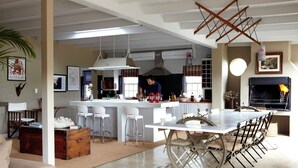 A spacious kitchen with a central island, bar stools, and a dining table with vintage-style chairs. - Explorers Club (Franschhoek)