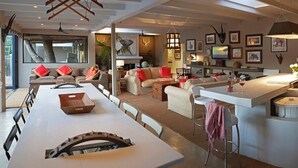 A spacious living area with a large dining table, a kitchen island, and a seating area with sofas. - Explorers Club (Franschhoek)