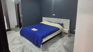 A bedroom with a bed, a nightstand, and a ceiling light. - COSY apartment in Abidjan (Abidjan)