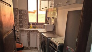 A compact kitchen with a washing machine, a stove, and a refrigerator. - COSY apartment in Abidjan (Abidjan)