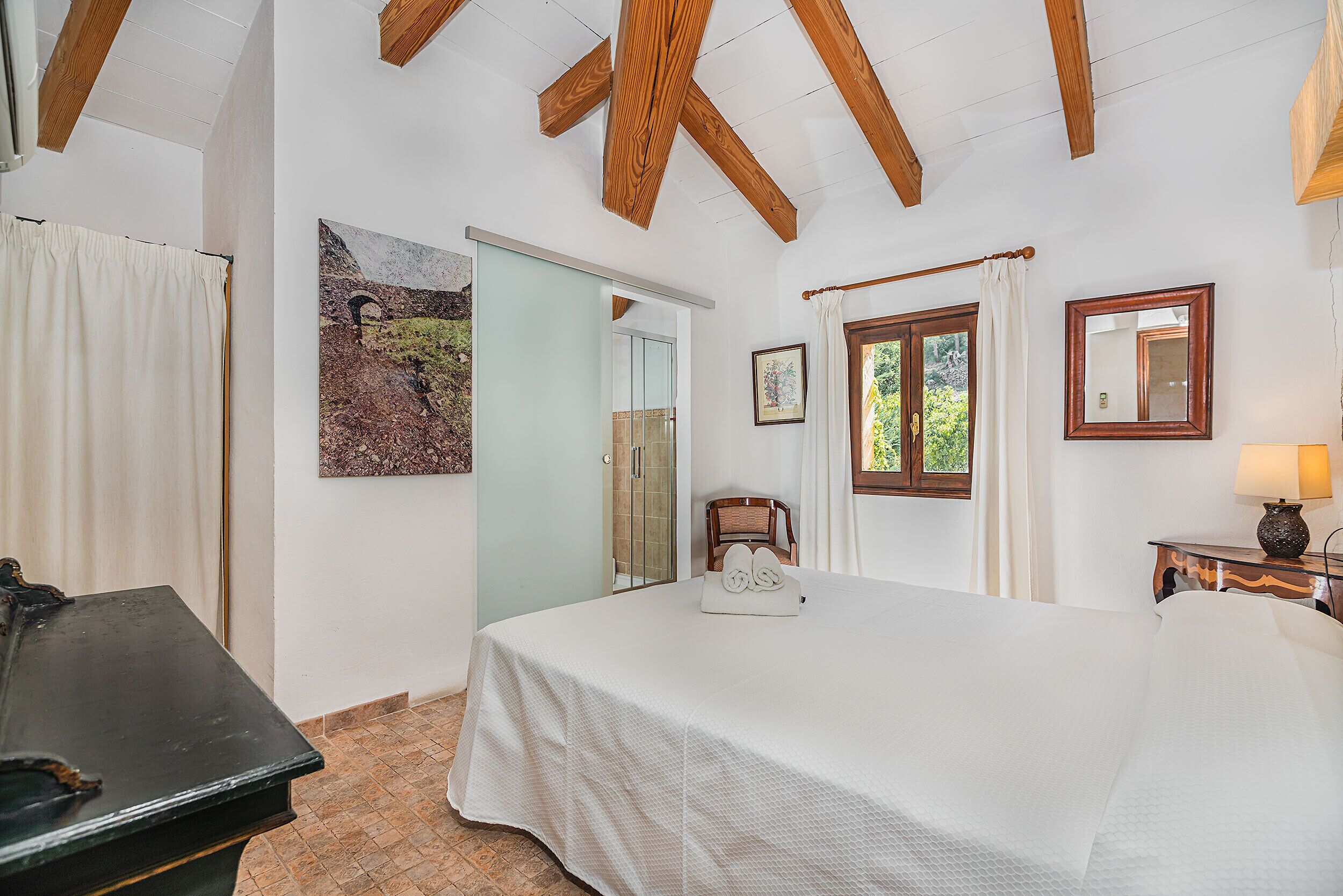 A bedroom with a bed, a chair, a desk, and a painting on the wall.