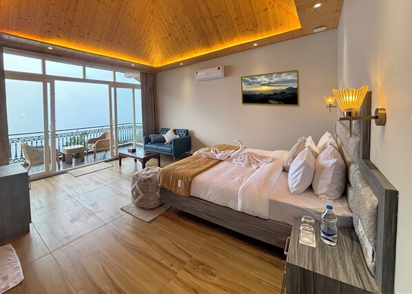 A modern bedroom with a large bed, a balcony with wicker furniture, and a view of the sky.