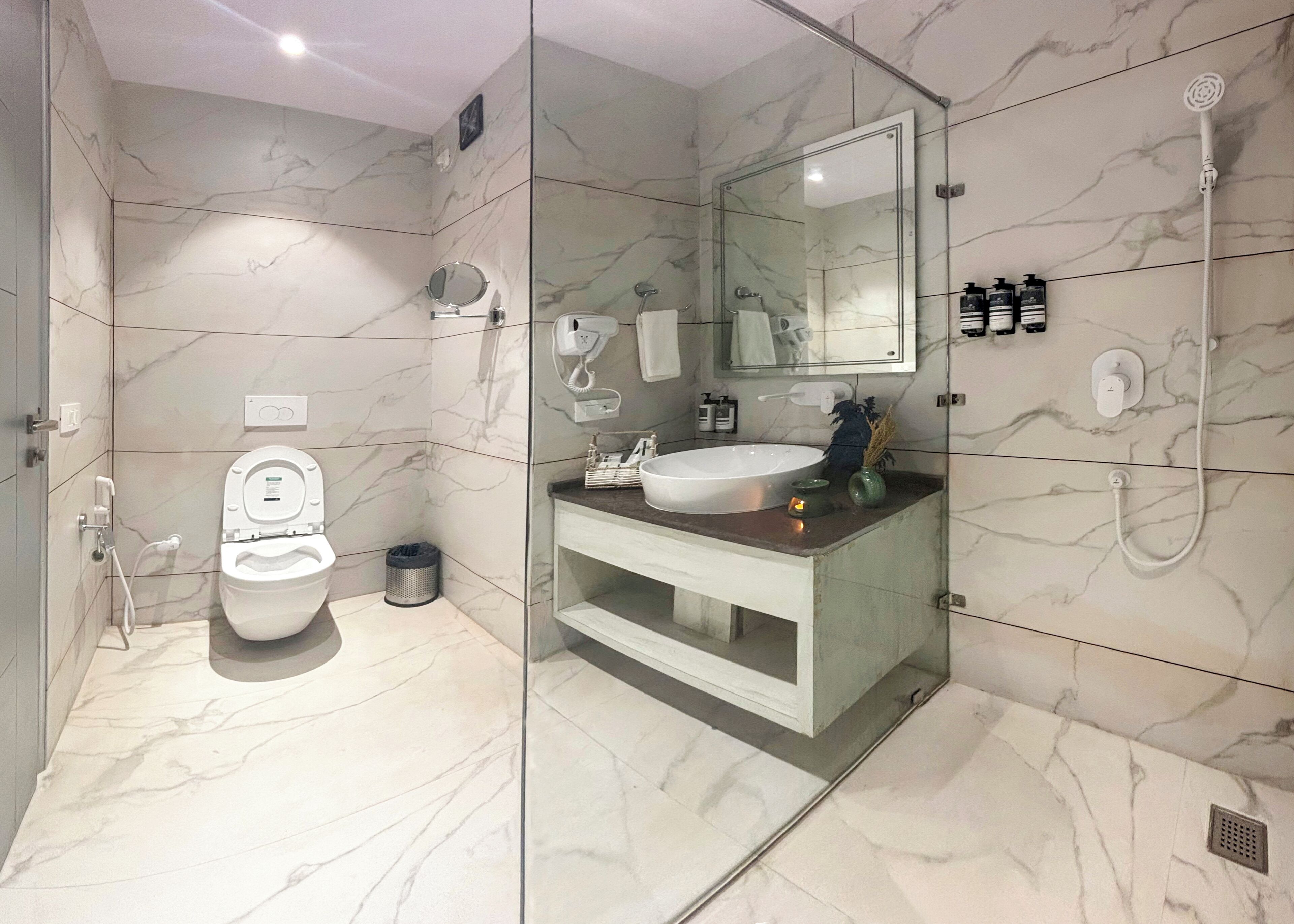 A modern bathroom with a glass-enclosed shower, a toilet, and a vanity with a sink and mirror.