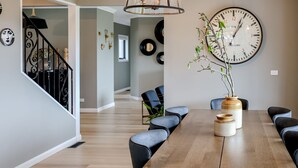 A dining area with a wooden table, black chairs, and a large wall clock.