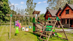 A playground with a wooden climbing structure, slides, and swings. - Stunning home in Mielenko with WiFi (Mielenko)
