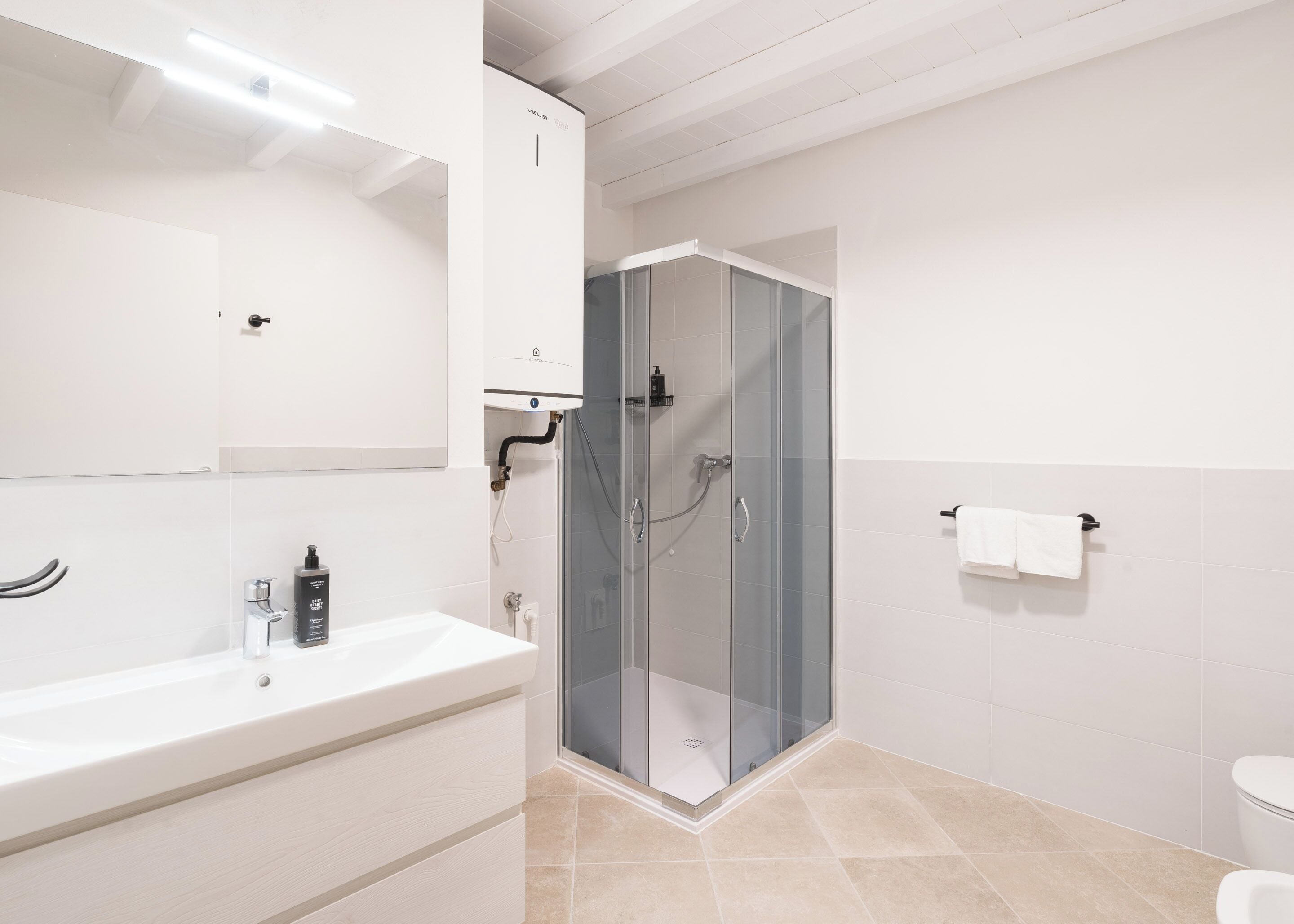 Ein modernes Badezimmer mit einer Duschkabine, einem weißen Waschbecken und einer Toilette.
