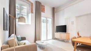 Una sala de estar moderna con sofá, una mesa de centro, televisor y un comedor con sillas y mesa.