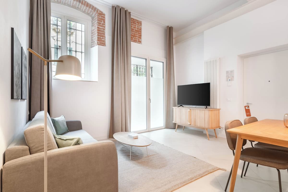 Ein modernes Wohnzimmer mit einer Couch, einem Couchtisch, einem Fernseher und einem Essbereich mit Stühlen und einem Tisch.