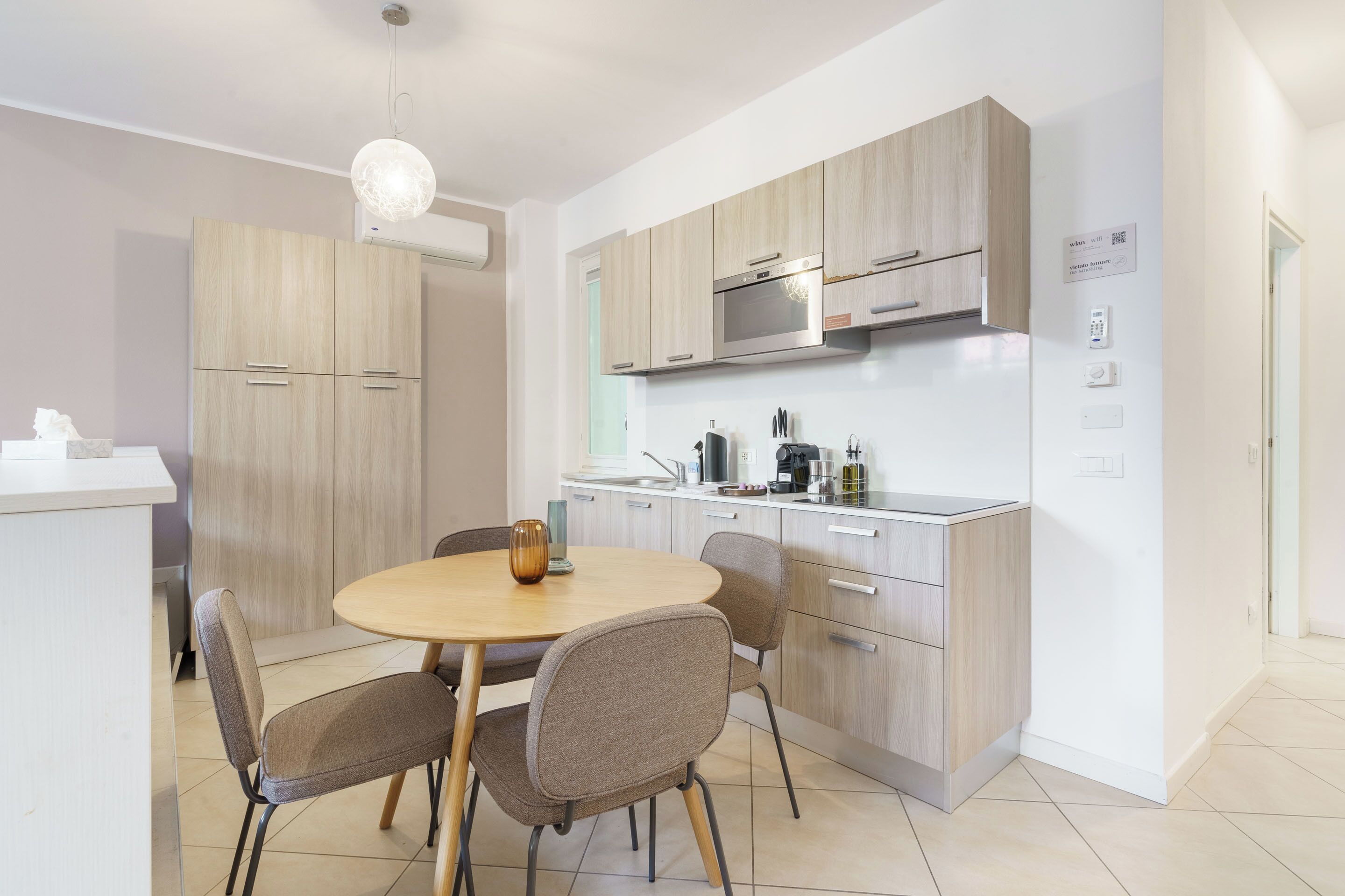 A modern kitchen with wooden cabinets, a built-in oven, and a dining area with a round table and chairs.