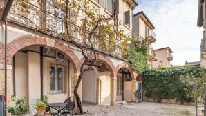 Un edificio con patio, que presenta un arco de ladrillo, una mesa con sillas y plantas en macetas.