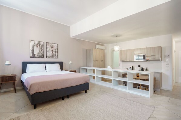 A modern bedroom with a large bed, bedside tables, and a built-in white shelving unit. - Limehome Verona La Vigna in Città (Verona)