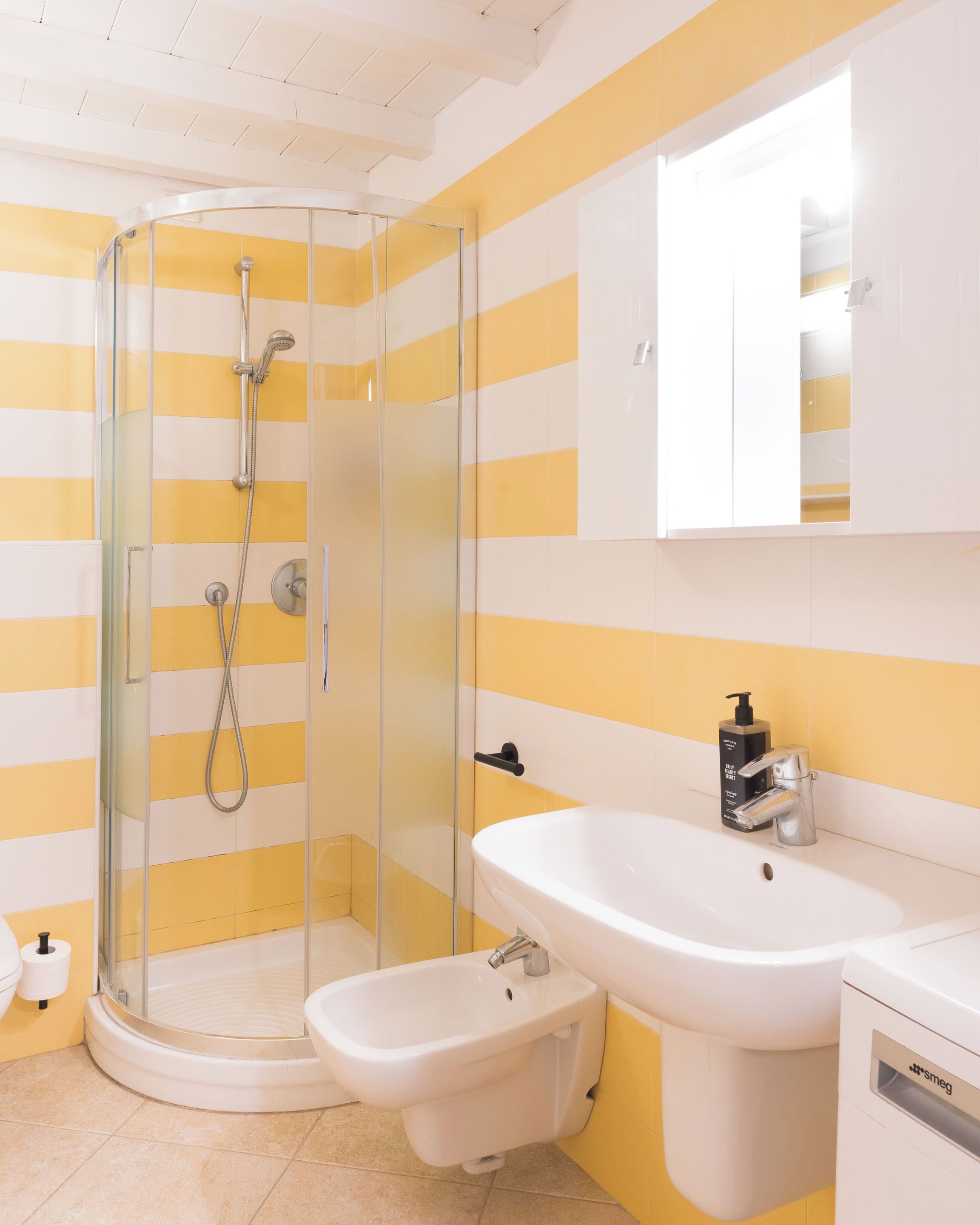A bathroom with a glass-enclosed shower, a white sink, and a toilet.