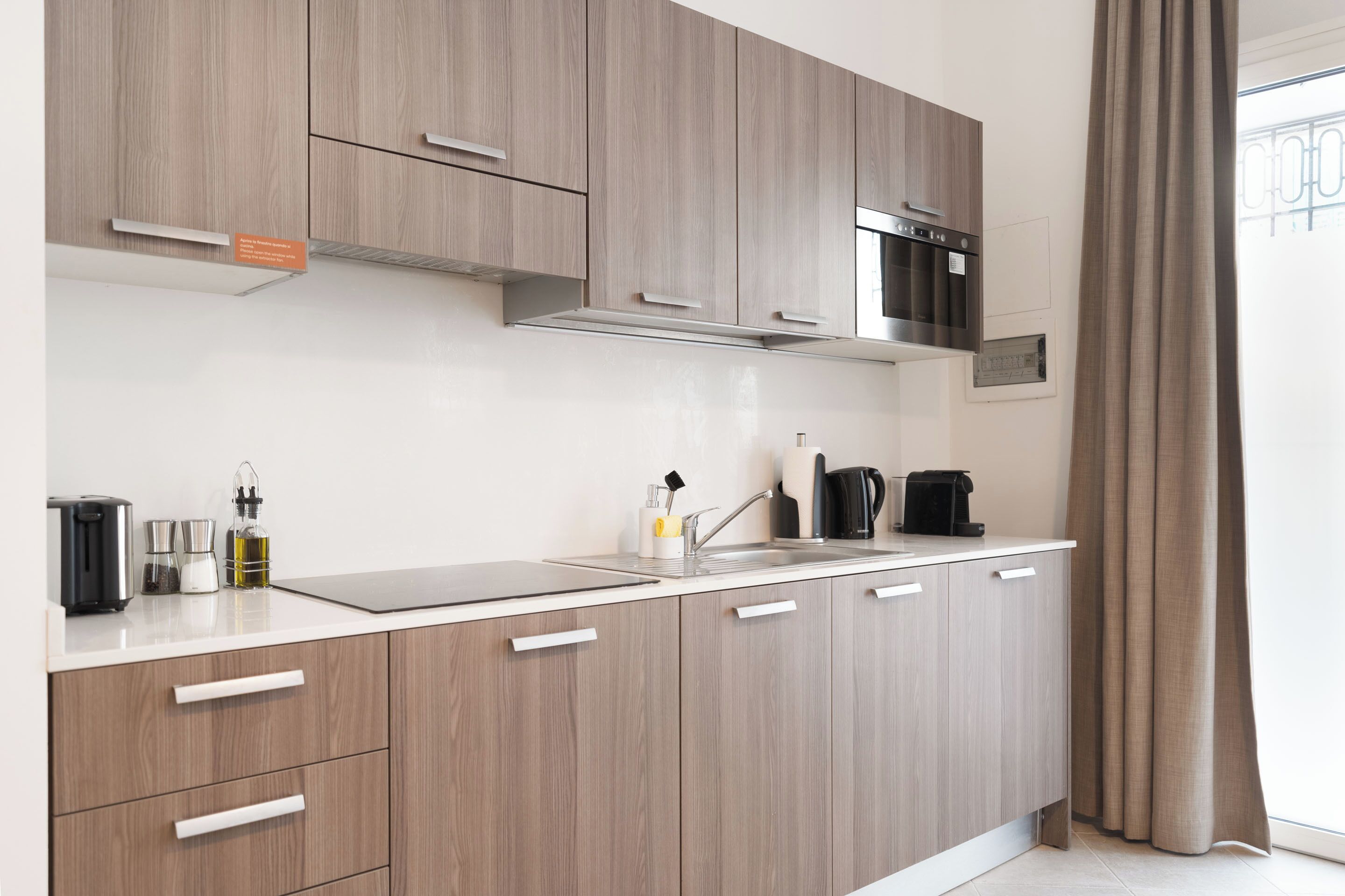 A modern kitchen with light wood cabinets, stainless steel appliances, and a white countertop.