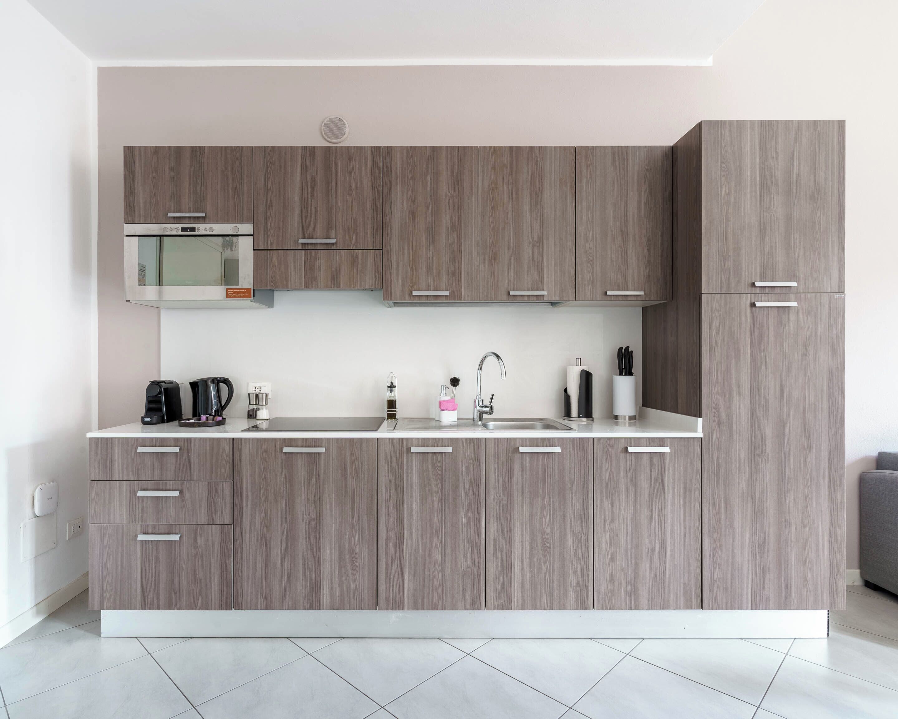 A modern kitchen with wooden cabinets, a built-in microwave, and a stainless steel sink.