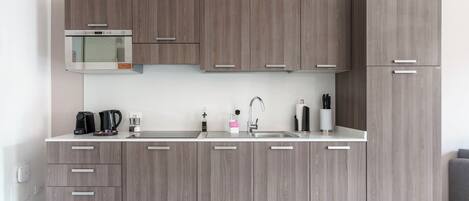 A modern kitchen with wooden cabinets, a built-in microwave, and a stainless steel sink.