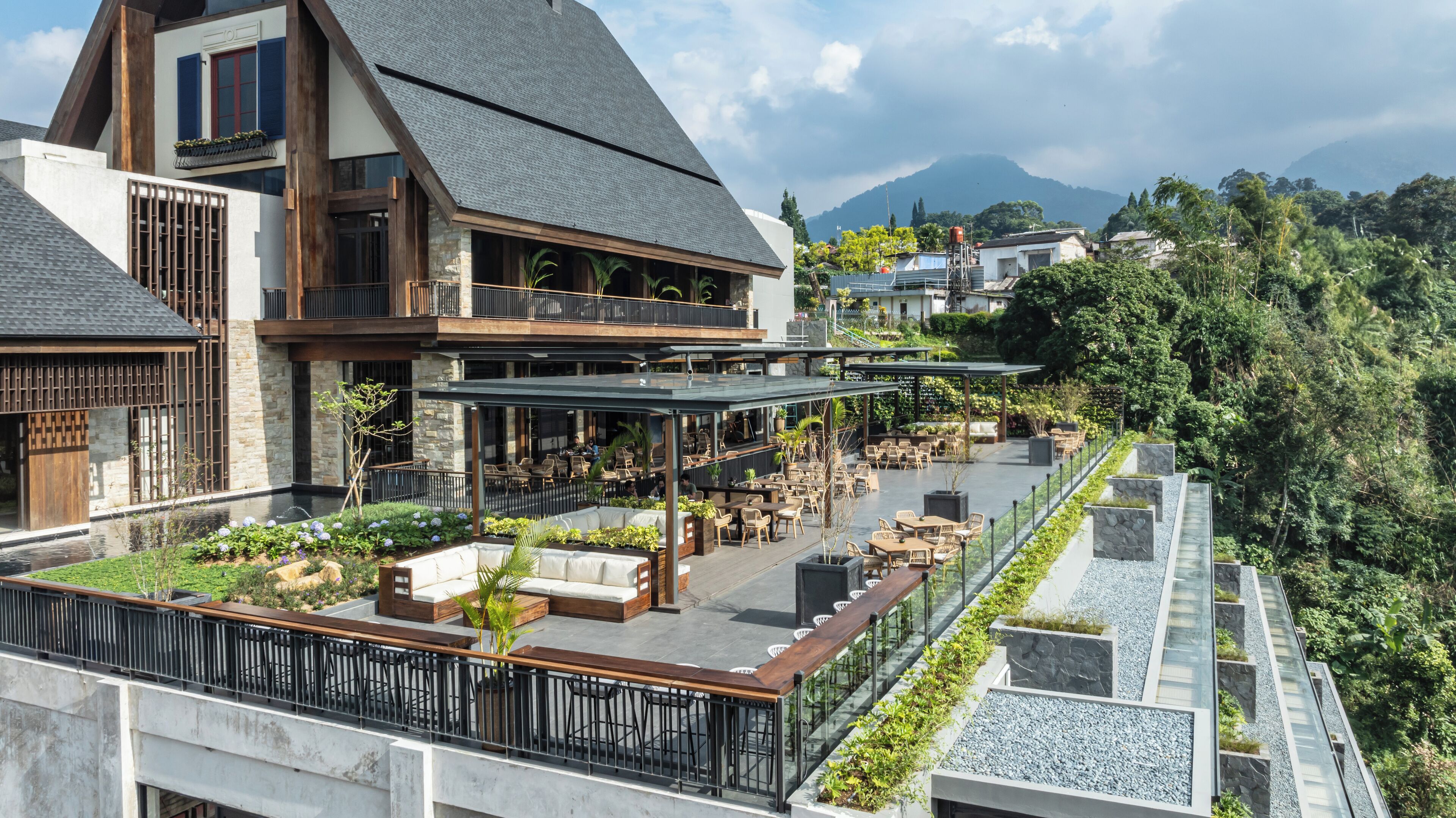 A modern building with a rooftop patio area featuring outdoor seating and a view of the surrounding landscape.
