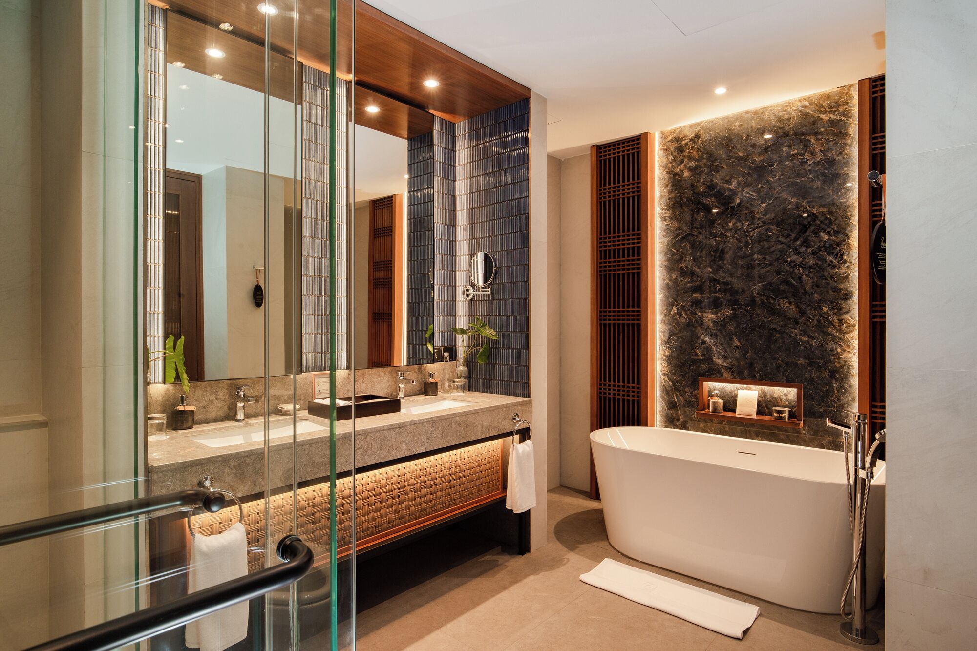 Un baño moderno con una bañera independiente, un espejo grande y una zona de ducha con mampara de cristal.