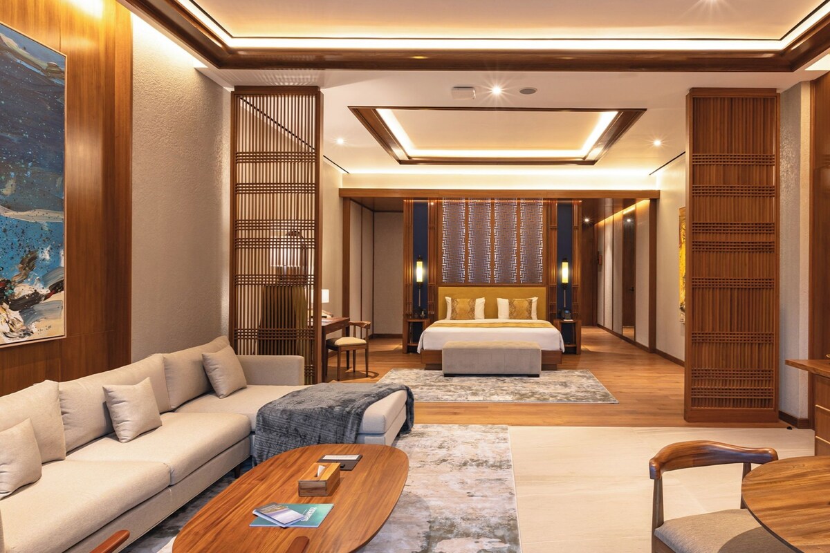 Una habitación de hotel moderna con sofá, mesa de comedor, cama y televisor.
