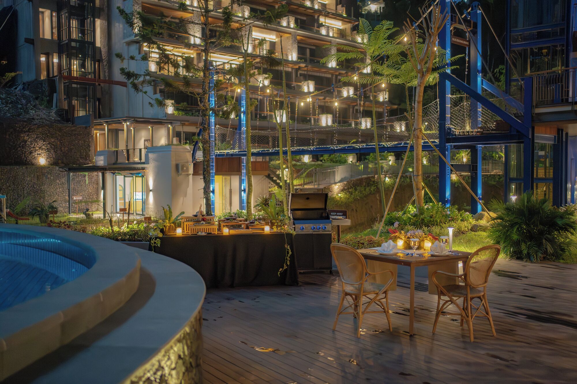 An outdoor dining area with a grill, wooden chairs, and a pool.