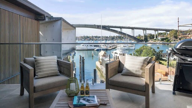 A balcony with two sofas facing a marina, a grill, and a view of a bridge. - Neighbouring Sydney Harbour Retreats for 12 guests (Drummoyne)