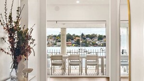A hallway leading to a balcony with a view of a harbor and buildings. - Neighbouring Sydney Harbour Retreats for 12 guests (Drummoyne)