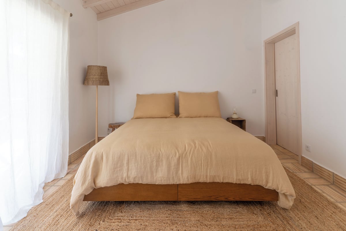 A bedroom with a bed, a nightstand, a lamp, and a door.