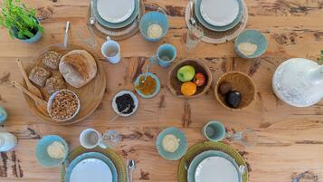 A wooden table with various food items, plates, and bowls.