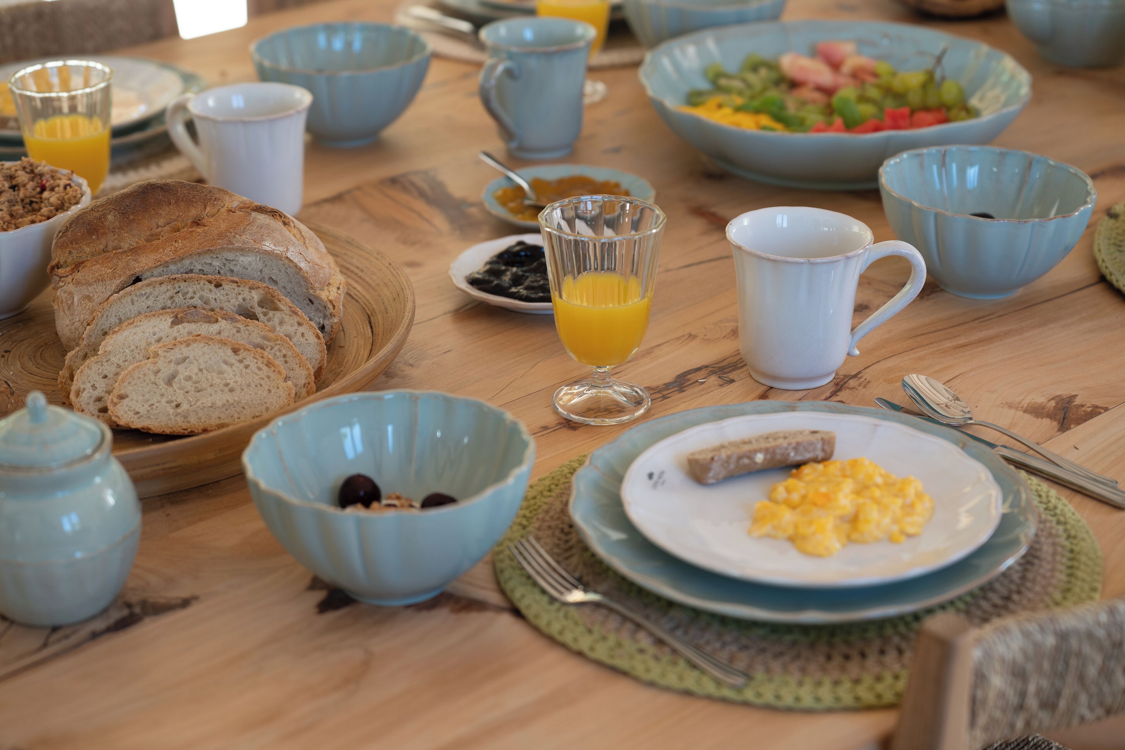 A breakfast setting with various dishes and drinks on a wooden table.