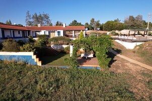 A house with a red-tiled roof, a patio with outdoor furniture, and a staircase leading to the entrance.