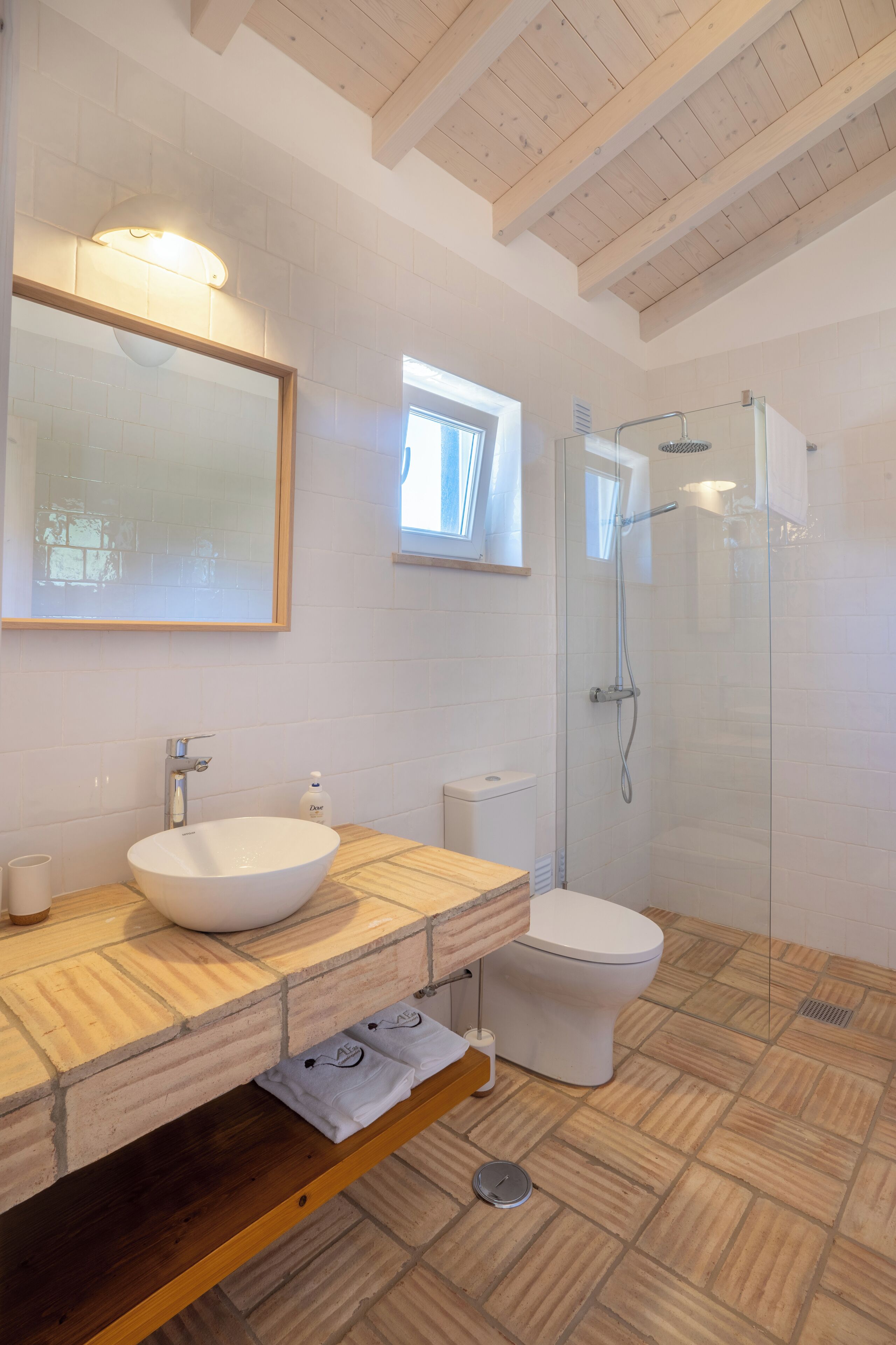 Un bagno moderno con un ampio specchio, un lavabo a incasso, un water e una doccia con pareti in vetro.