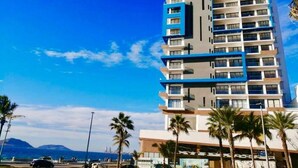 A multi-story hotel with a modern design, featuring balconies and a flat roof.