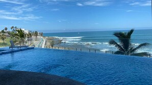 A pool with a view of the ocean and beach.