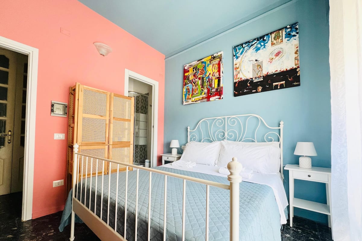 Un dormitorio con cama, mesitas de noche, armario y dos cuadros decorativos.