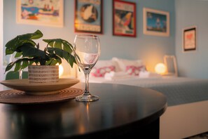 Una habitación con una cama, una mesita de noche con un vaso de agua, una planta en maceta y una obra de arte en la pared.