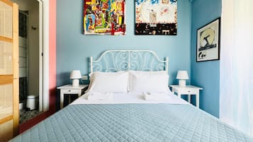 A bedroom with a bed, two bedside tables, and two wall-mounted paintings.