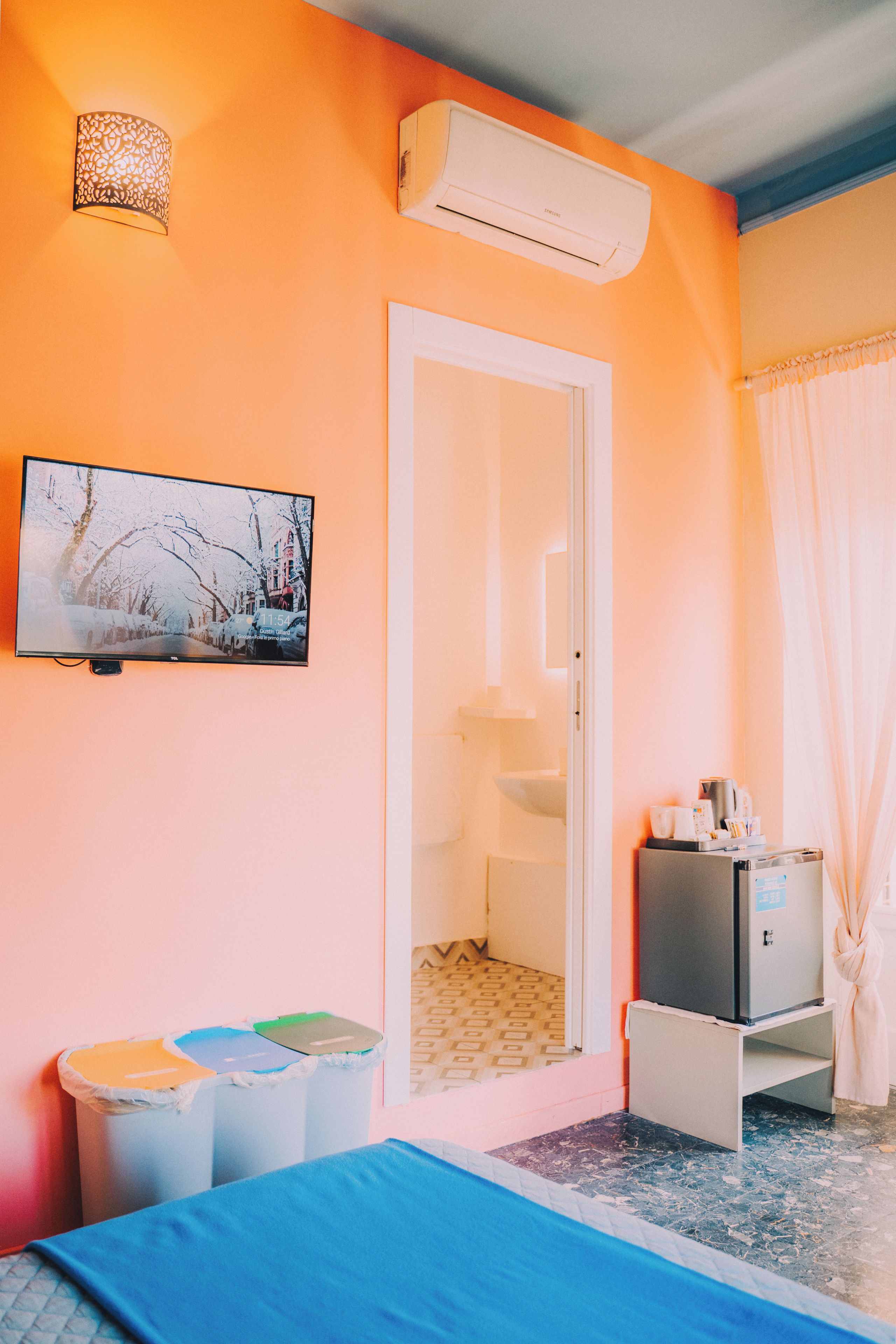 Una habitación de hotel con cama, televisión, armario, escritorio con computadora y baño.