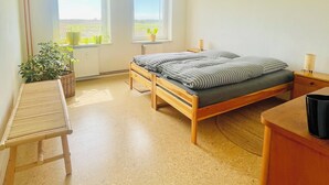 A bedroom with a wooden bed, two windows, a small table, and a radiator. - "MTS Haus - Zettemin" Family-friendly vacation apartments in Mecklenburg (Zettemin)