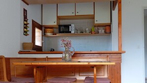 A kitchen with wooden cabinets, a microwave, and a vase with flowers on the counter. - Renovated 2P apartment on slopes, quiet, Pra Loup (Pra-Loup)