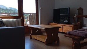 A cozy living room with a wooden table, a sofa, and a TV on a wooden stand. - Renovated 2P apartment on slopes, quiet, Pra Loup (Pra-Loup)