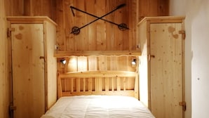 A wooden room with a bed, wooden cabinets, and a ceiling with a wooden beam structure.