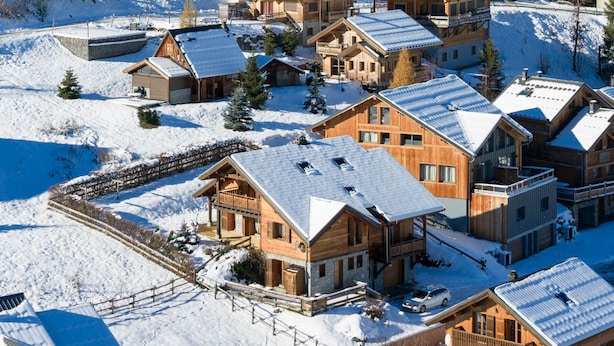 A snow-covered resort with multiple wooden cabins and a ski lift visible in the background. - Cozy 4* chalet near slopes with parking and wifi for 14 guests (Le Corbier)